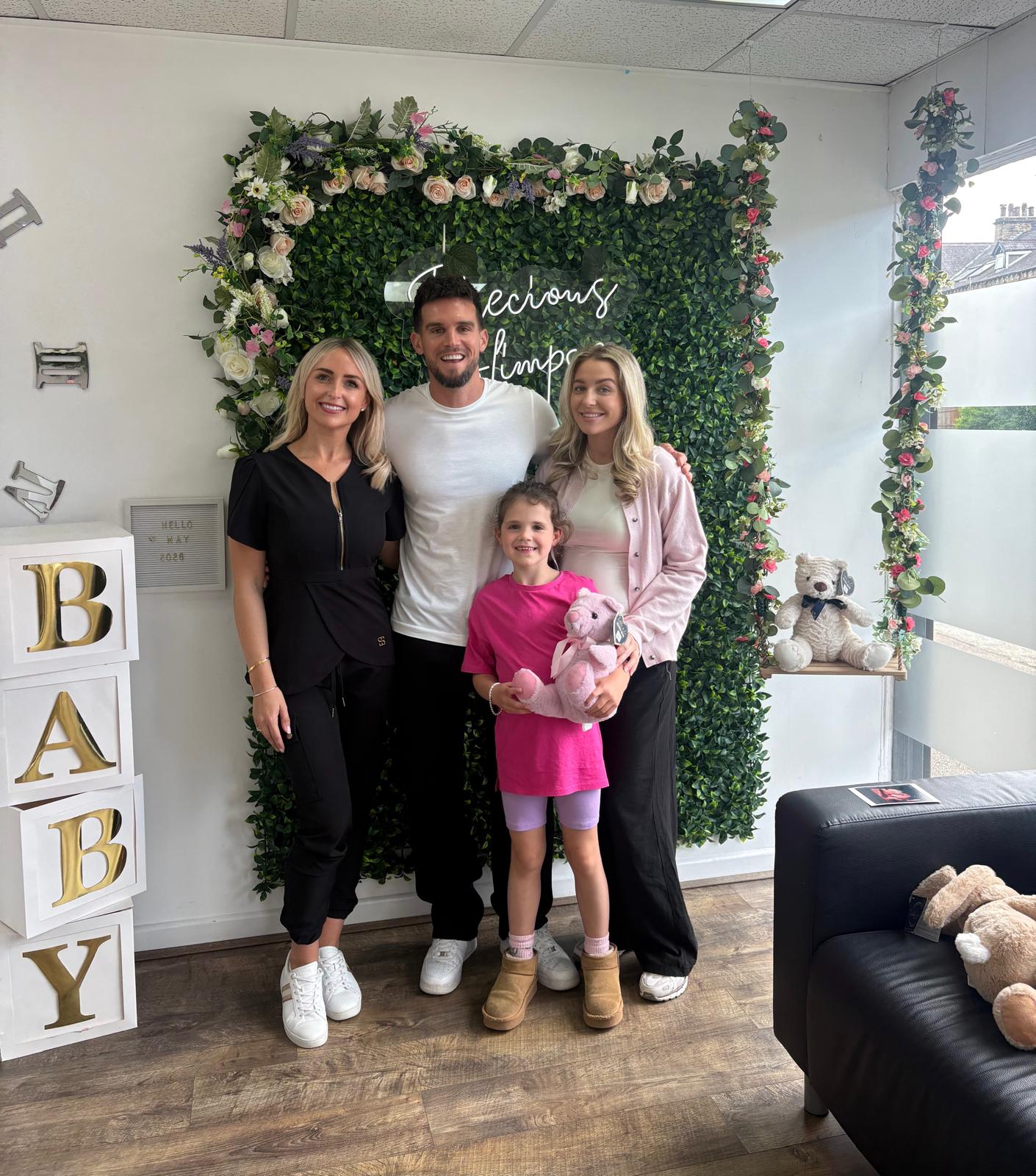 A family at the Precious Glimpse flower wall after their scan