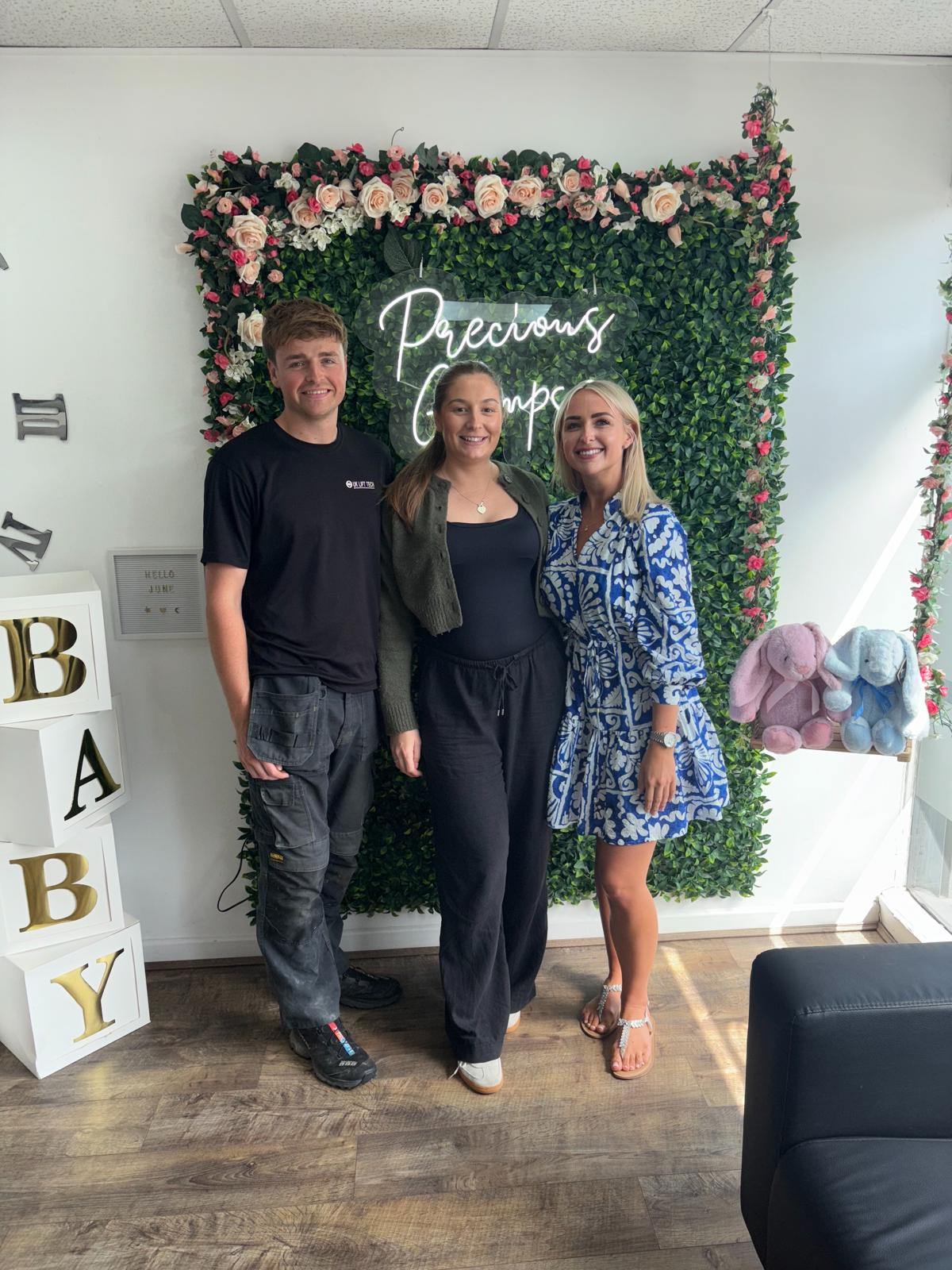 An expectant couple at the Precious Glimpse flower wall after their scan