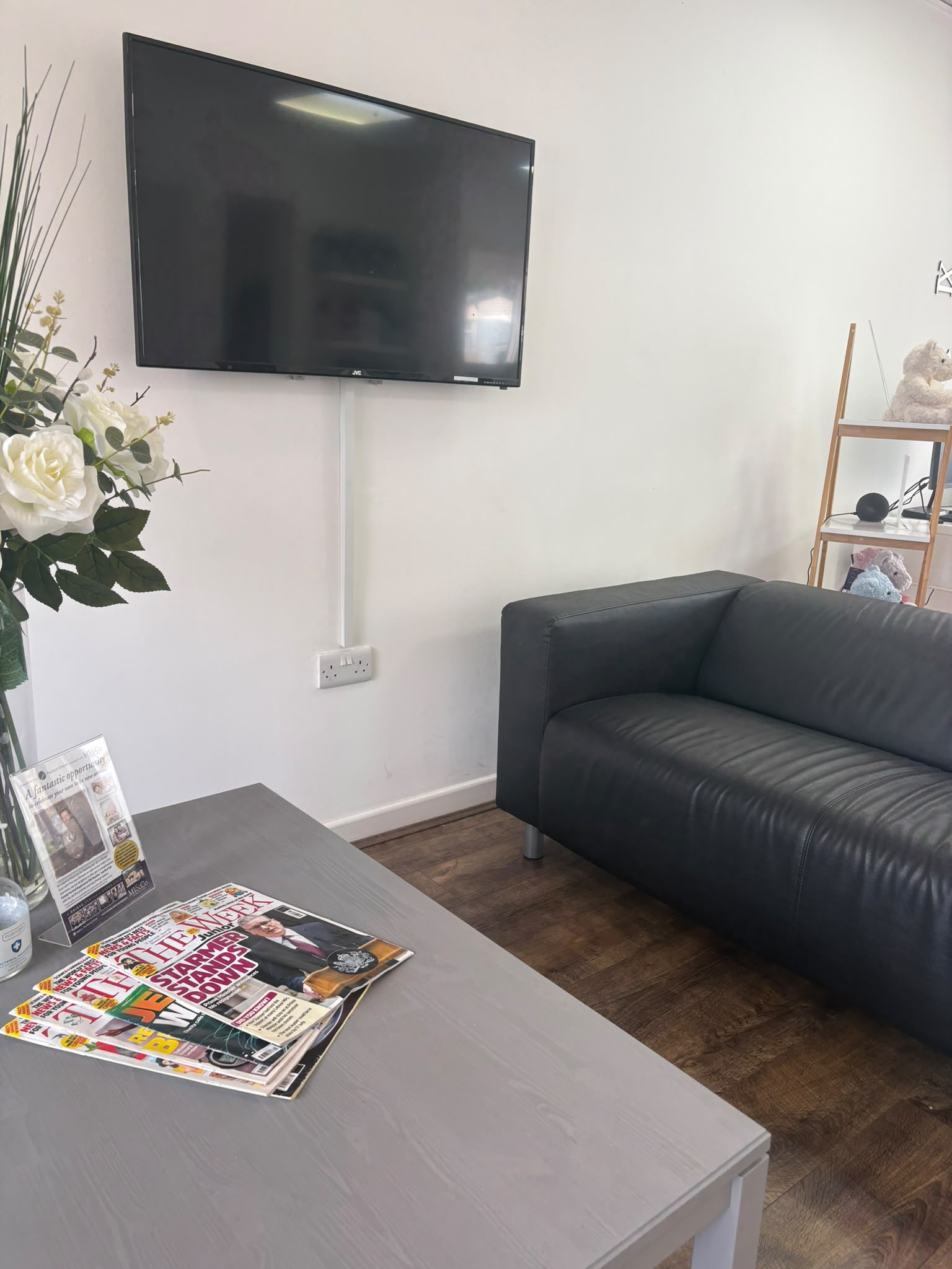 The waiting area at Precious Glimpse, with a sofa, magazines and a wall-mounted viewing screen